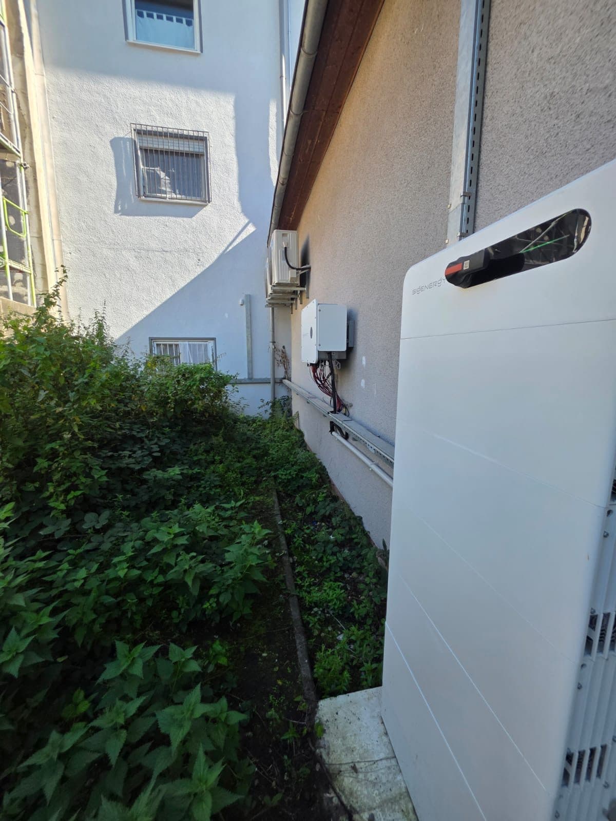 Gesamtansicht der Anlage: Speicherturm im Vordergrund, dahinter Wechselrichter an der Fassade