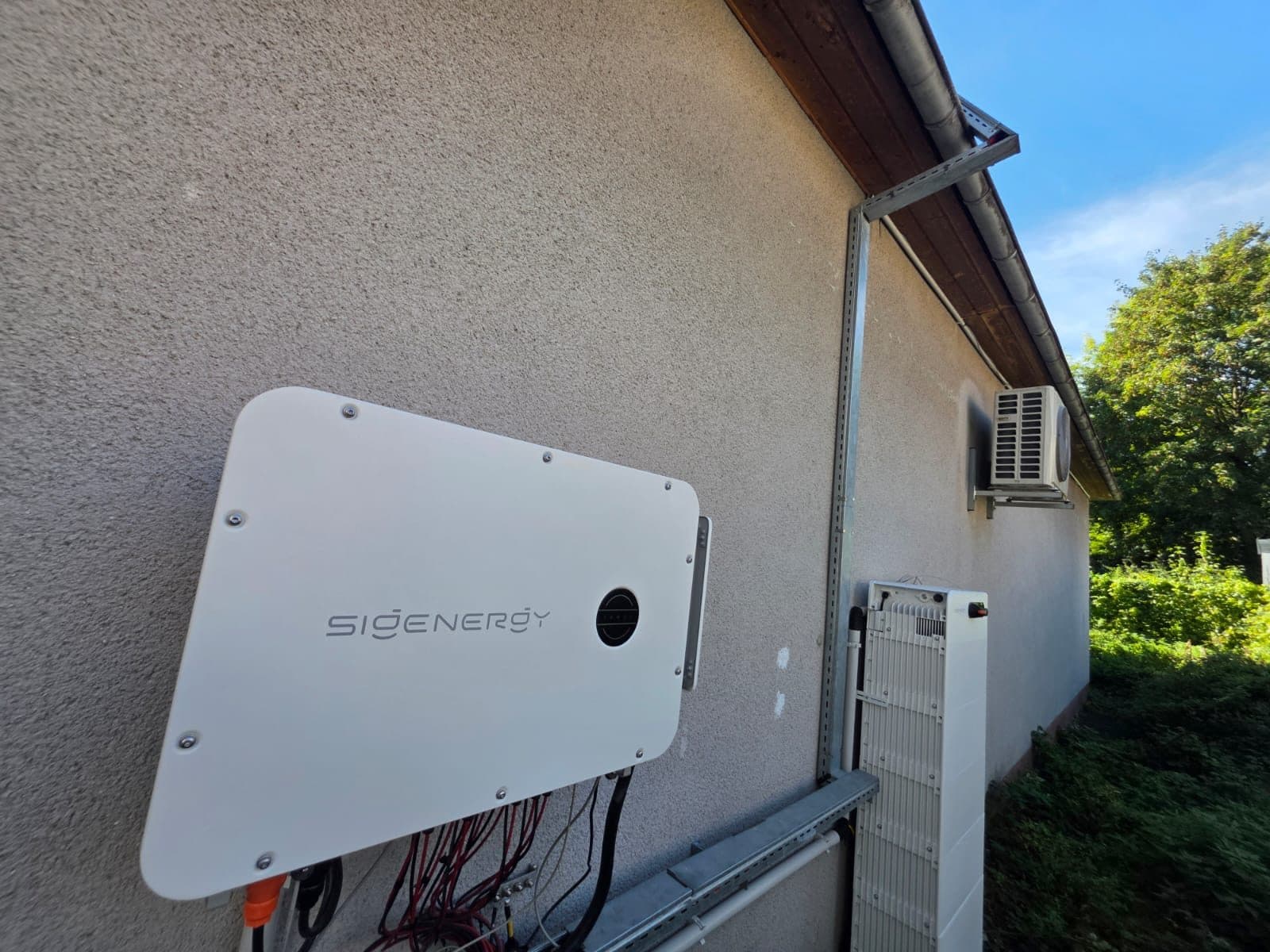 Sigenergy Hybridwechselrichter an der Außenwand eines Gewerbegebäudes, daneben der Speicherturm